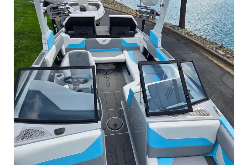Slide: The Image of 2023 ATX Surf Boats 20 Type-S interior with blue and gray seating, docked by a lake. - 22