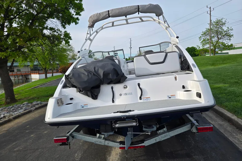 Slide: The Image of 2021 Yamaha Boats AR250 on trailer, parked near a grassy area and trees. - 2