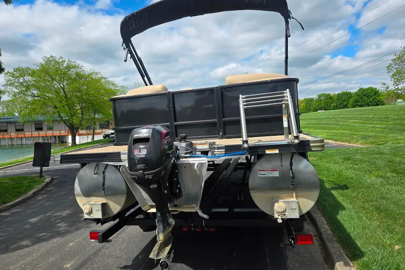 Slide: The Image of 2021 Barletta C22QC pontoon boat with Mercury outboard motor, parked on a trailer. - 2