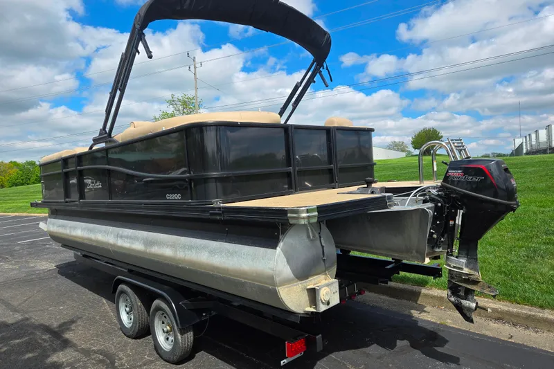 Slide: The Image of 2021 Barletta C22QC pontoon boat on trailer, parked outdoors under a blue sky. - 3