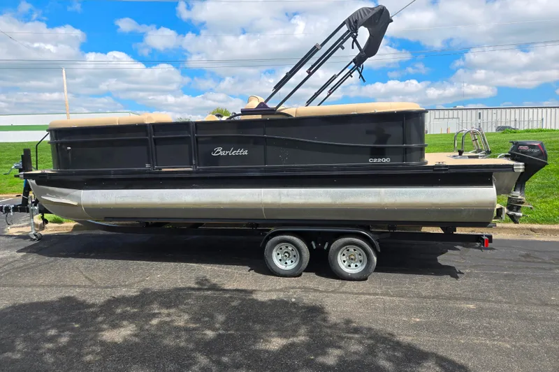 Slide: The Image of 2021 Barletta C22QC pontoon boat on trailer, parked outdoors under a blue sky. - 4