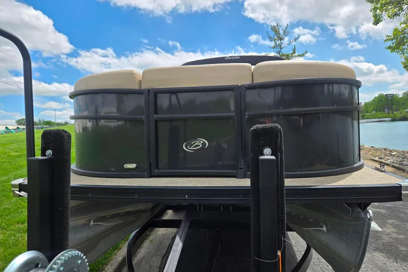 Slide: The Image of 2021 Barletta C22QC pontoon boat on trailer, parked near a lake under a blue sky. - 6