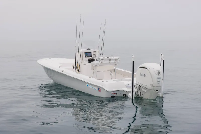Slide: The Image of 2026 Contender 24 Bay boat with fishing rods and Yamaha engine on calm water. - 1