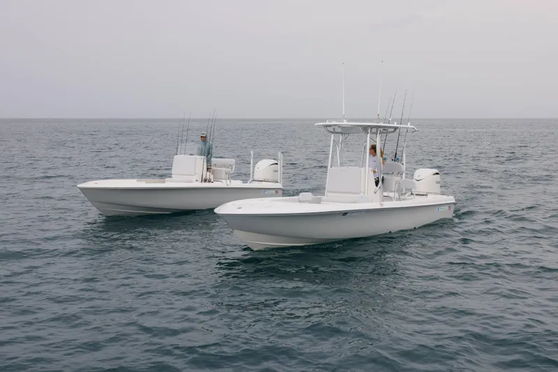 Slide: The Image of Two Contender 24 Bay boats on open water, 2026 model, with fishing gear. - 2