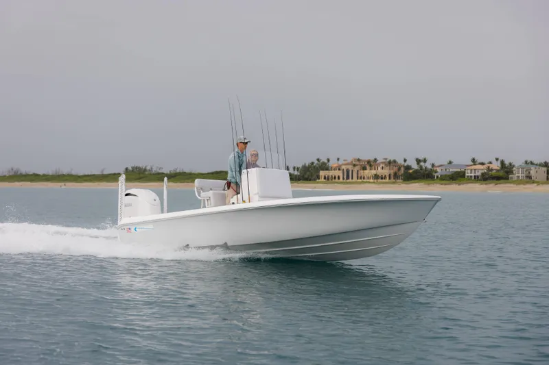 Slide: The Image of 2026 Contender 24 Bay boat cruising on calm waters near a coastal shoreline. - 7