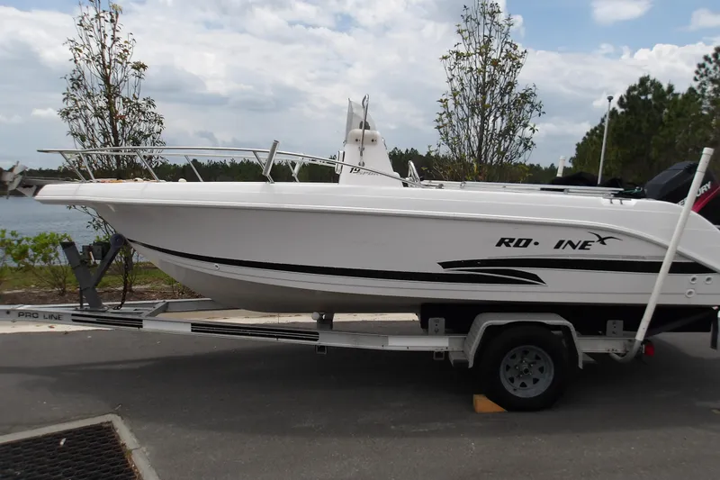 The Image of 2000 Pro-Line 19 Sport boat on trailer, parked near a lake. - 0