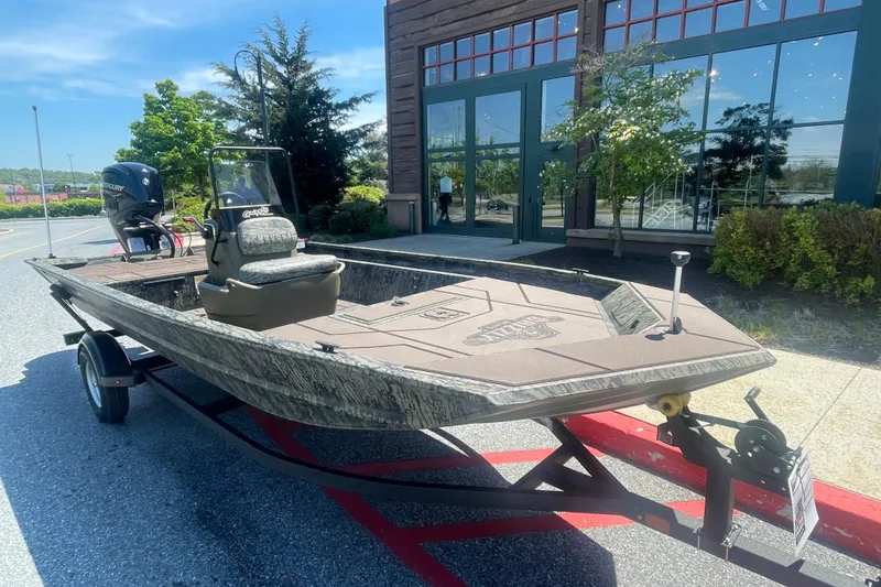Slide: The Image of 2026 Tracker Grizzly 1860 CC boat on trailer, parked outdoors near a building. - 2