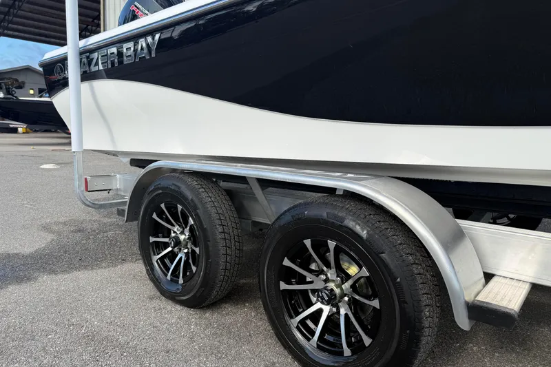 Slide: The Image of 2026 Blazer PureBay 2400 boat on trailer with sleek black wheels. - 2