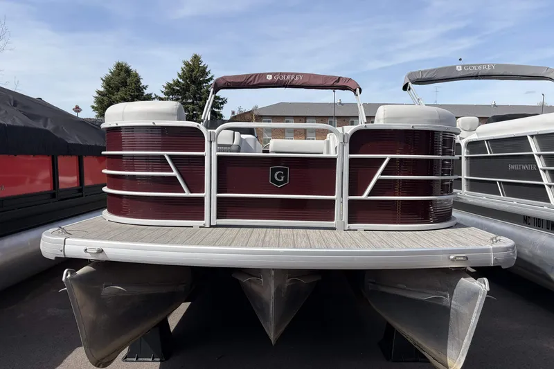 The Image of 2022 Godfrey Sweetwater 2286 C pontoon boat with maroon exterior, docked outdoors. - 0