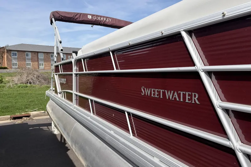Slide: The Image of 2022 Godfrey Sweetwater 2286 C pontoon boat with maroon exterior, parked near buildings. - 18