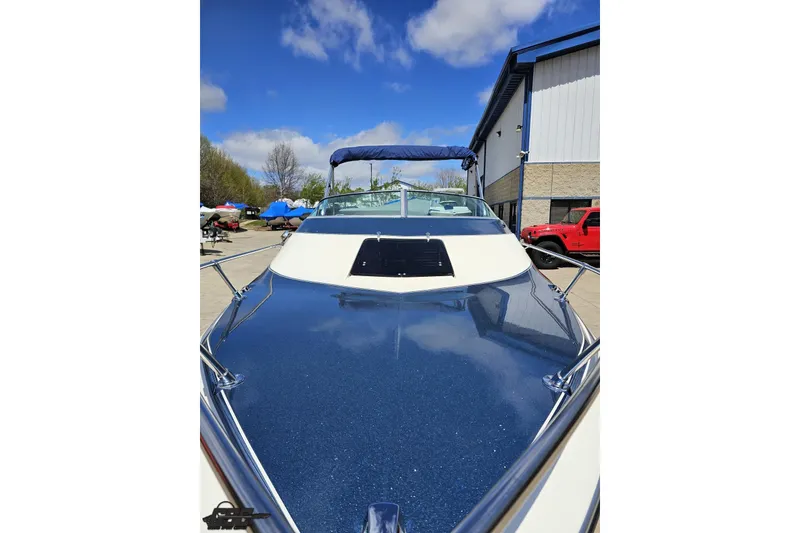 Slide: The Image of 1988 Glastron/Carlson CVX-23 boat with blue deck, parked outdoors under clear sky. - 11