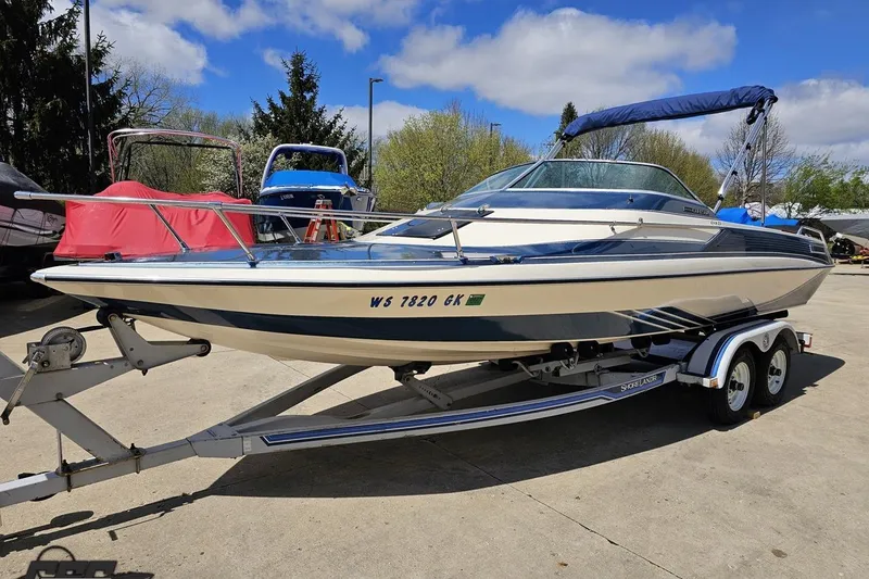 Slide: The Image of 1988 Glastron/Carlson CVX-23 boat on trailer, parked outdoors under a blue sky. - 13