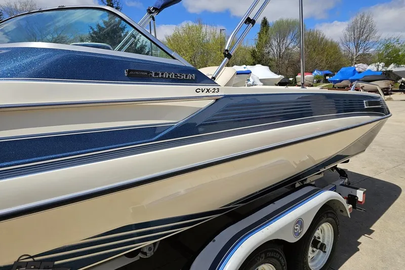 Slide: The Image of 1988 Glastron/Carlson CVX-23 boat on trailer, blue and white design, parked outdoors. - 18