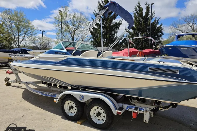 Slide: The Image of 1988 Glastron/Carlson CVX-23 boat on trailer, parked outdoors under a blue sky. - 21