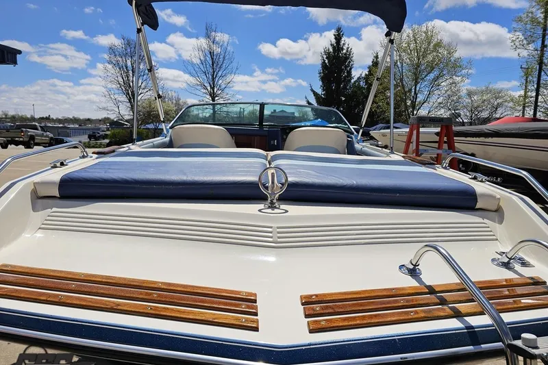 Slide: The Image of 1988 Glastron/Carlson CVX-23 boat with blue upholstery and wooden accents, docked outdoors. - 25