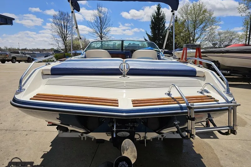 Slide: The Image of 1988 Glastron/Carlson CVX-23 boat with blue accents, parked outdoors on a sunny day. - 26