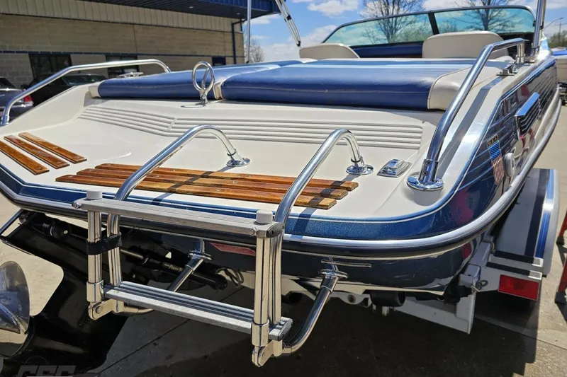 Slide: The Image of 1988 Glastron/Carlson CVX-23 boat with chrome ladder and wooden accents, parked outdoors. - 29