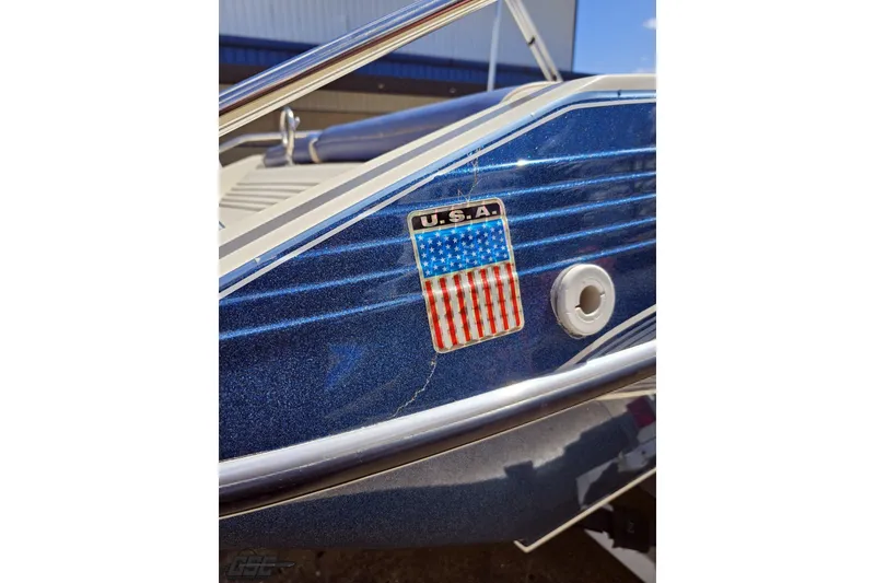 Slide: The Image of 1988 Glastron/Carlson CVX-23 boat with USA flag emblem on blue exterior. - 30
