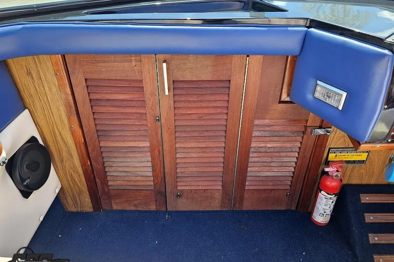 Slide: The Image of 1988 Glastron/Carlson CVX-23 boat interior with wooden panels and blue upholstery. - 47