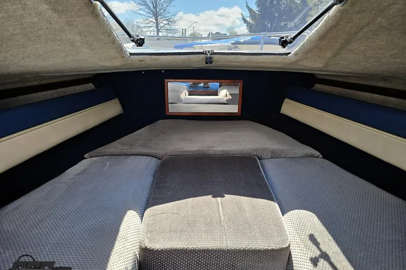Slide: The Image of Interior cabin of a 1988 Glastron/Carlson CVX-23 boat, featuring cushioned seating and a window. - 68