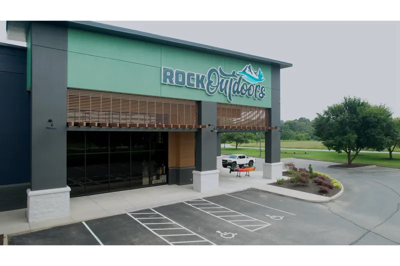 Slide: The Image of Outdoor store entrance with "Rock Outdoors" sign, featuring a modern design and spacious parking area. - 11