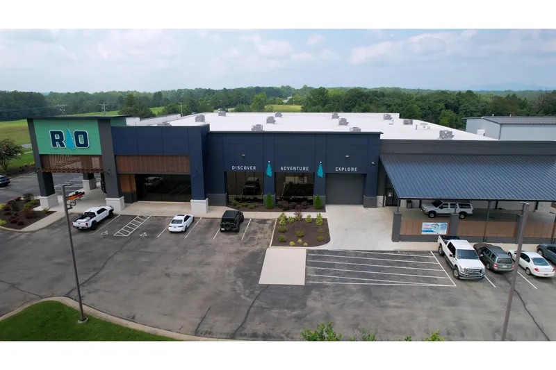 Slide: The Image of Aerial view of modern commercial building with parking lot, featuring "Discover Adventure Explore" signage. - 12