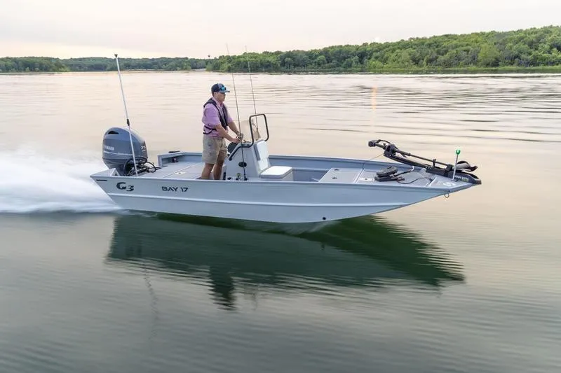 Slide: The Image of 2026 G3 Bay 17 boat cruising on a calm lake with a person steering. - 5