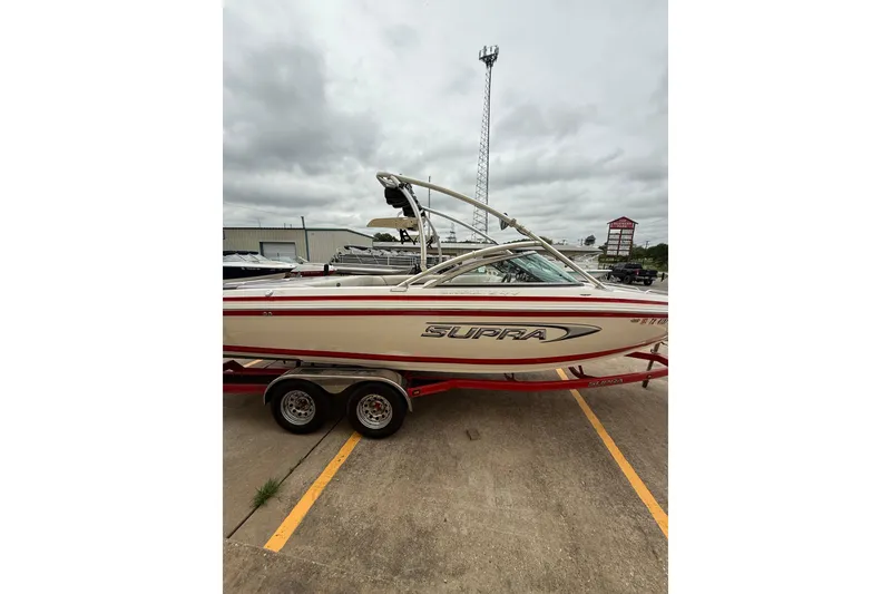 Slide: The Image of 2005 Supra Sunsport 24 V boat on trailer in parking lot. - 3