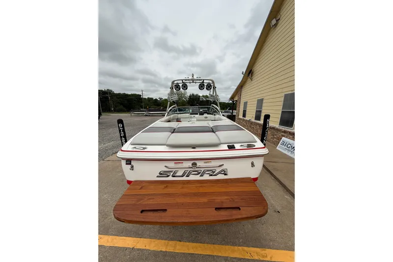 Slide: The Image of 2005 Supra Sunsport 24 V boat, rear view, parked outdoors with wooden swim platform. - 5
