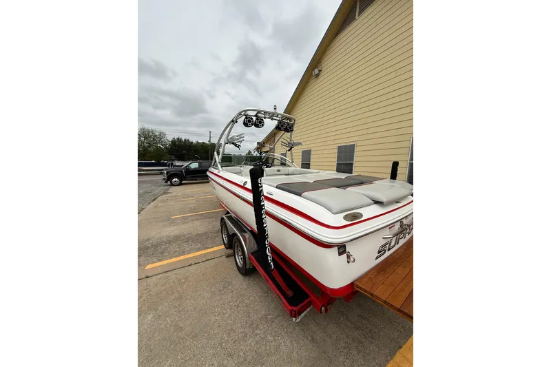 Slide: The Image of 2005 Supra Sunsport 24 V boat on trailer, parked beside a building. - 6