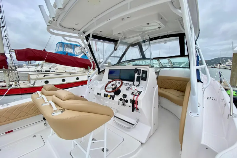 Slide: The Image of 2006 Donzi 38 ZSF boat cockpit with beige seating and modern controls at a marina. - 27