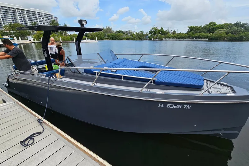 Slide: The Image of 2023 Argonaut 260 boat docked, featuring sleek design and blue seating, with people onboard. - 1