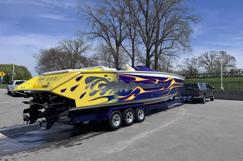 Slide: The Image of Colorful 2000 Python Offshore boat on trailer, vibrant flame design, parked outdoors. - 12