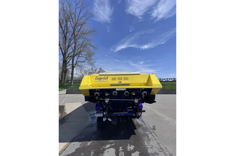 Slide: The Image of Yellow 2000 Python Offshore boat parked, rear view, under clear blue sky. - 13