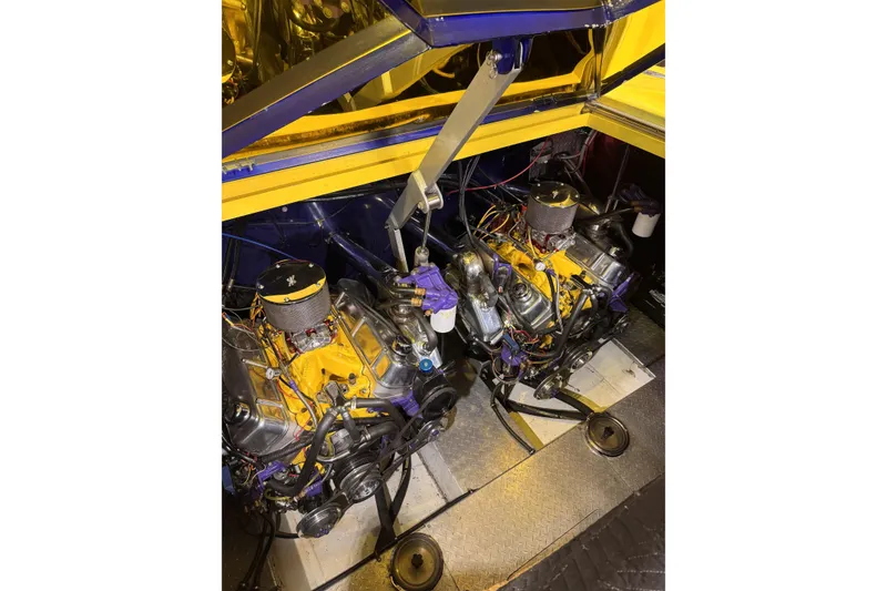 Slide: The Image of Engine compartment of a 2000 Python Offshore boat, showcasing dual engines and vibrant yellow accents. - 19
