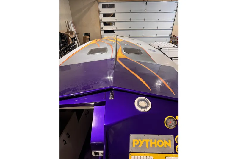 Slide: The Image of Purple and orange 2000 Python Offshore boat in a garage setting. - 23