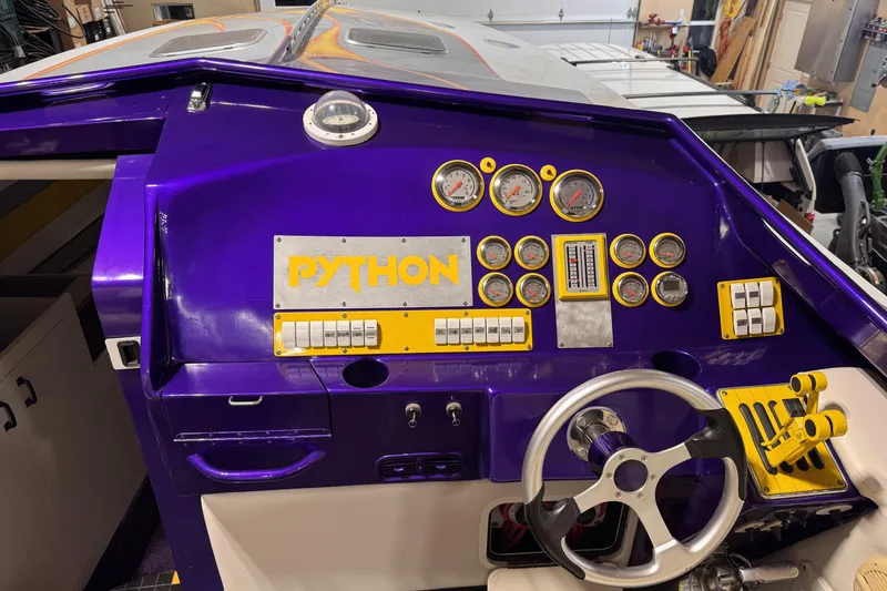 Slide: The Image of Purple dashboard of a 2000 Python Offshore boat with gauges and steering wheel. - 24