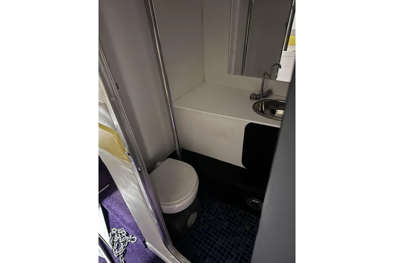 Slide: The Image of Compact bathroom in a 2000 Python Offshore boat, featuring a toilet and sink. - 29