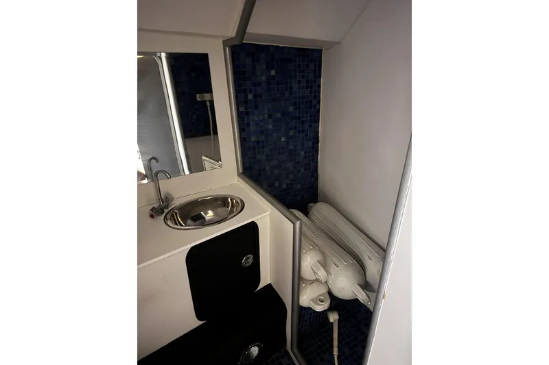 Slide: The Image of Compact bathroom in a 2000 Python Offshore boat with sink and blue tile accents. - 30