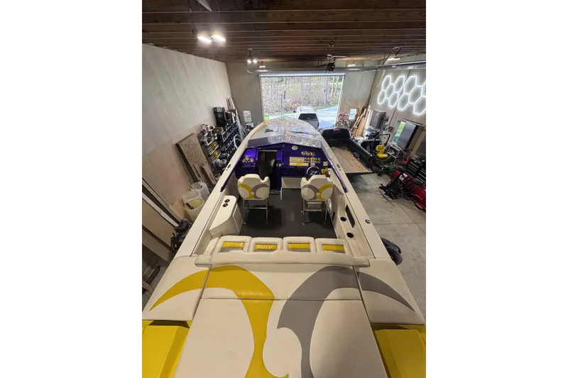 Slide: The Image of 2000 Python Offshore boat in garage, featuring yellow and white seating and modern design. - 32
