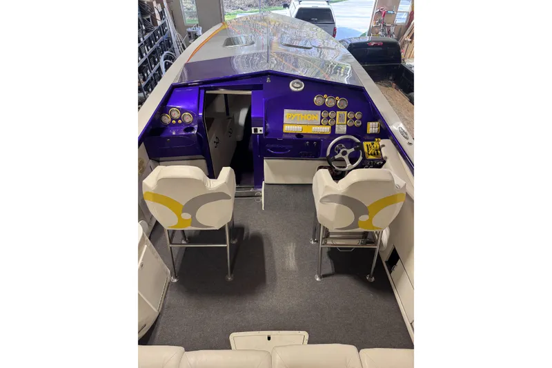 Slide: The Image of 2000 Python Offshore boat interior with purple dashboard and white seating. - 33