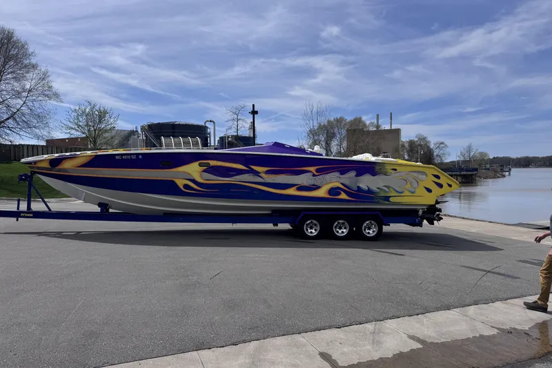 Slide: The Image of 2000 Python Offshore boat with vibrant flame design on trailer by waterfront. - 5