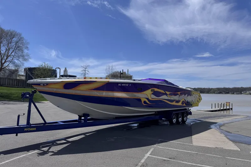 Slide: The Image of A 2000 Python Offshore boat with vibrant graphics on a trailer by a lake. - 6