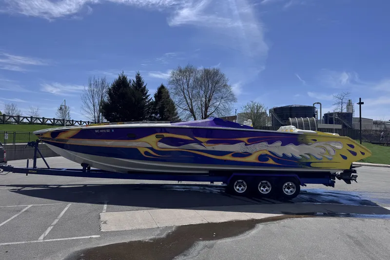 Slide: The Image of 2000 Python Offshore boat with vibrant flame design on trailer under clear sky. - 8