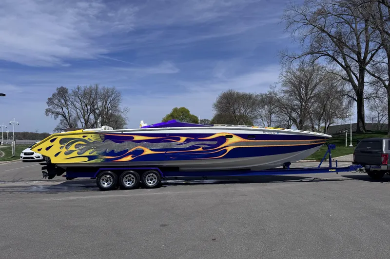 Slide: The Image of Colorful 2000 Python Offshore boat with flame design on trailer, parked outdoors. - 9