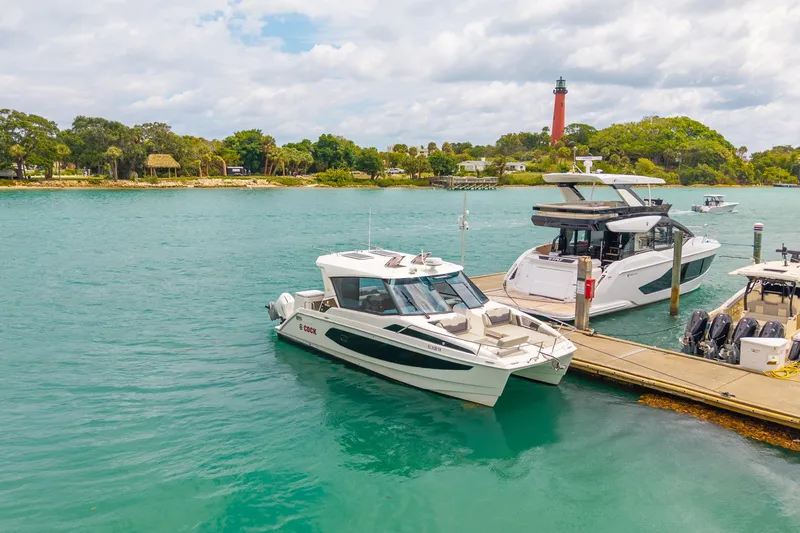 Slide: The Image of Aquila 36 Cruiser 2025 docked by a scenic waterfront with a lighthouse. - 5