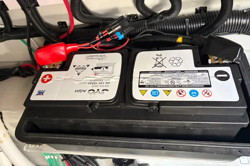 Slide: The Image of Battery compartment of 2025 Aquila 36 Cruiser with connected cables and safety labels. - 60