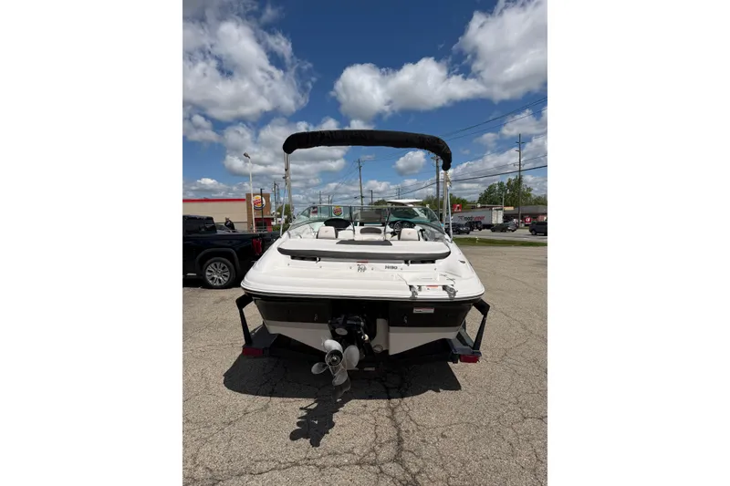 Slide: The Image of 2011 Four Winns H190 boat with canopy, parked outdoors under a partly cloudy sky. - 3