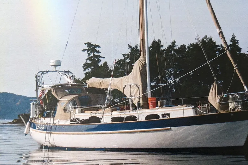 The Image of 1983 Valiant Cutter sailboat anchored near forested shoreline. - 0