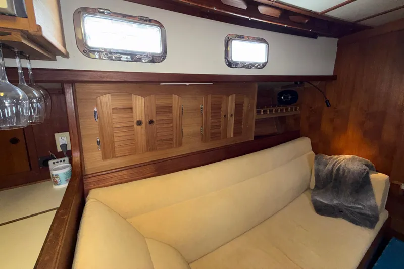 Slide: The Image of Interior of 1983 Valiant Cutter yacht with beige sofa, wooden cabinets, and porthole windows. - 10